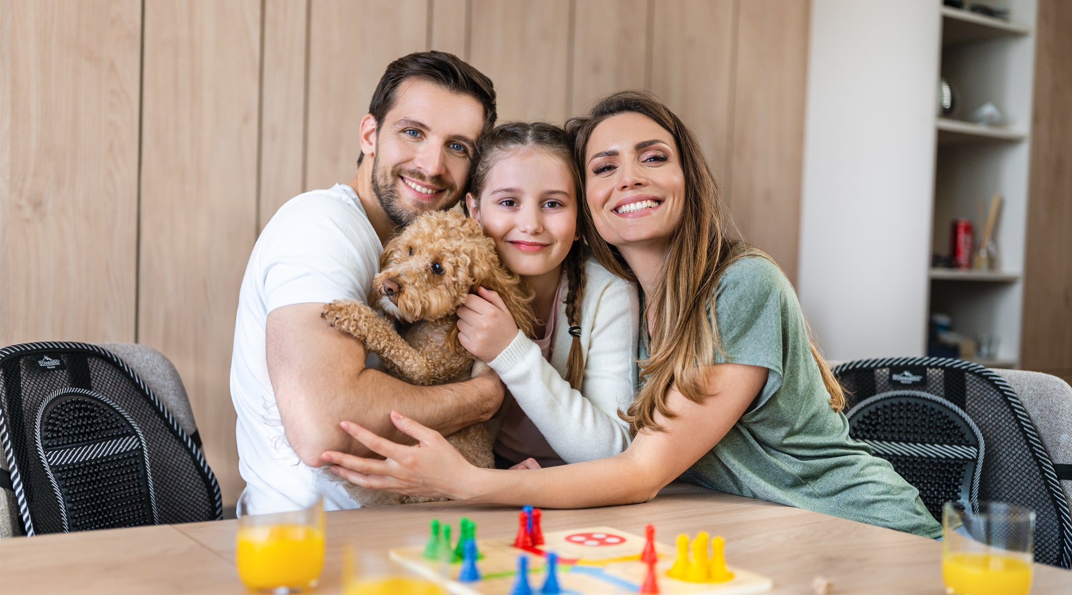 happy family of three sitting at table with mesh back support on chair for extra comfort