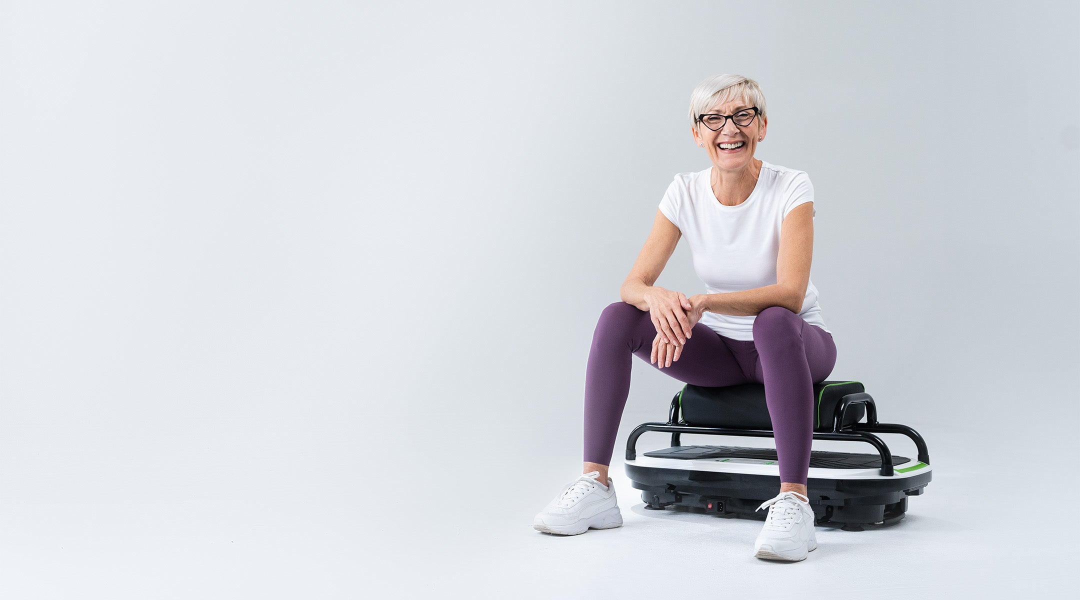 woman smiling and sitting on vibrating exercise machine with seat