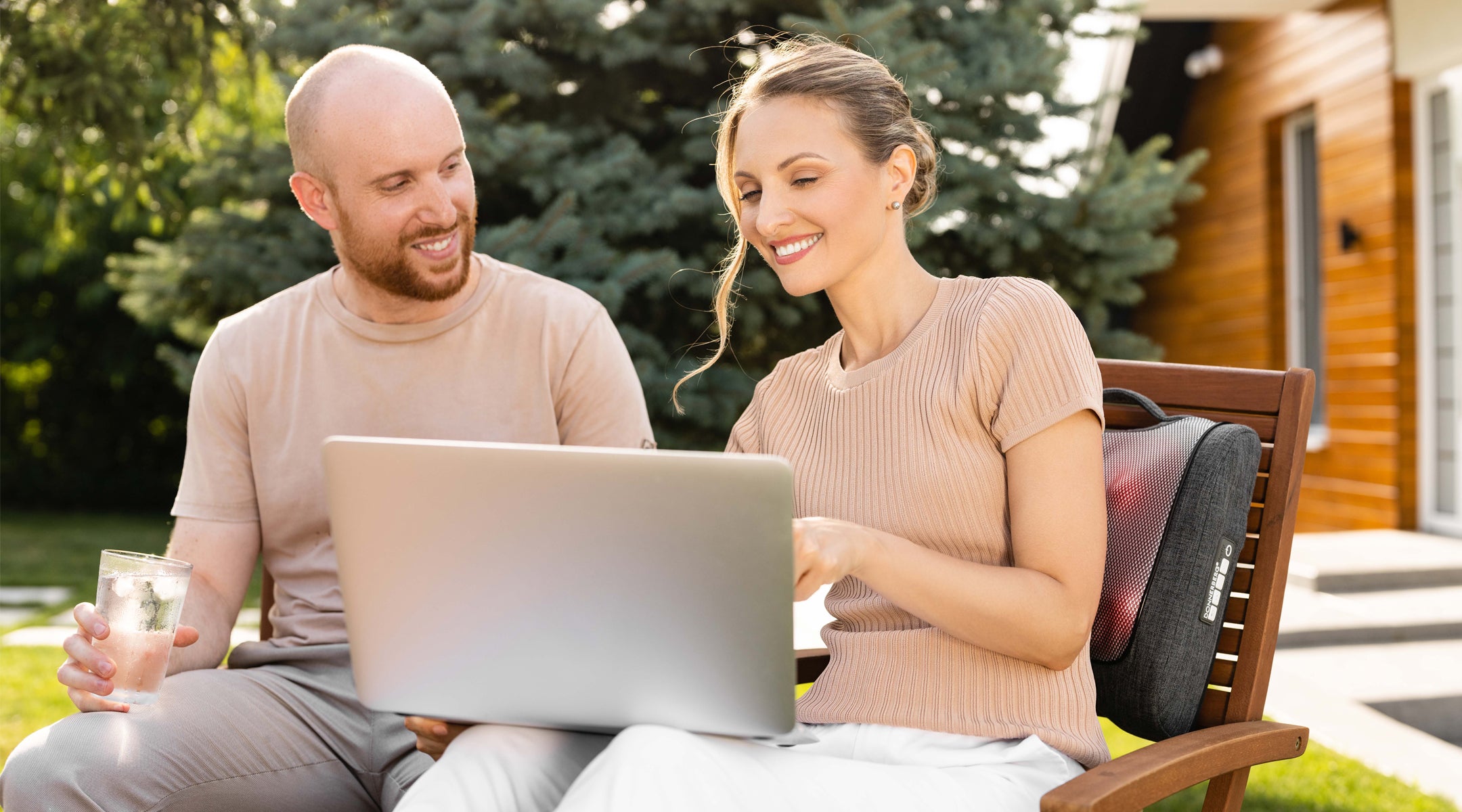 man and woman sitting outdoors while enjoying soothing massage with Donnerberg back massager featuring heat