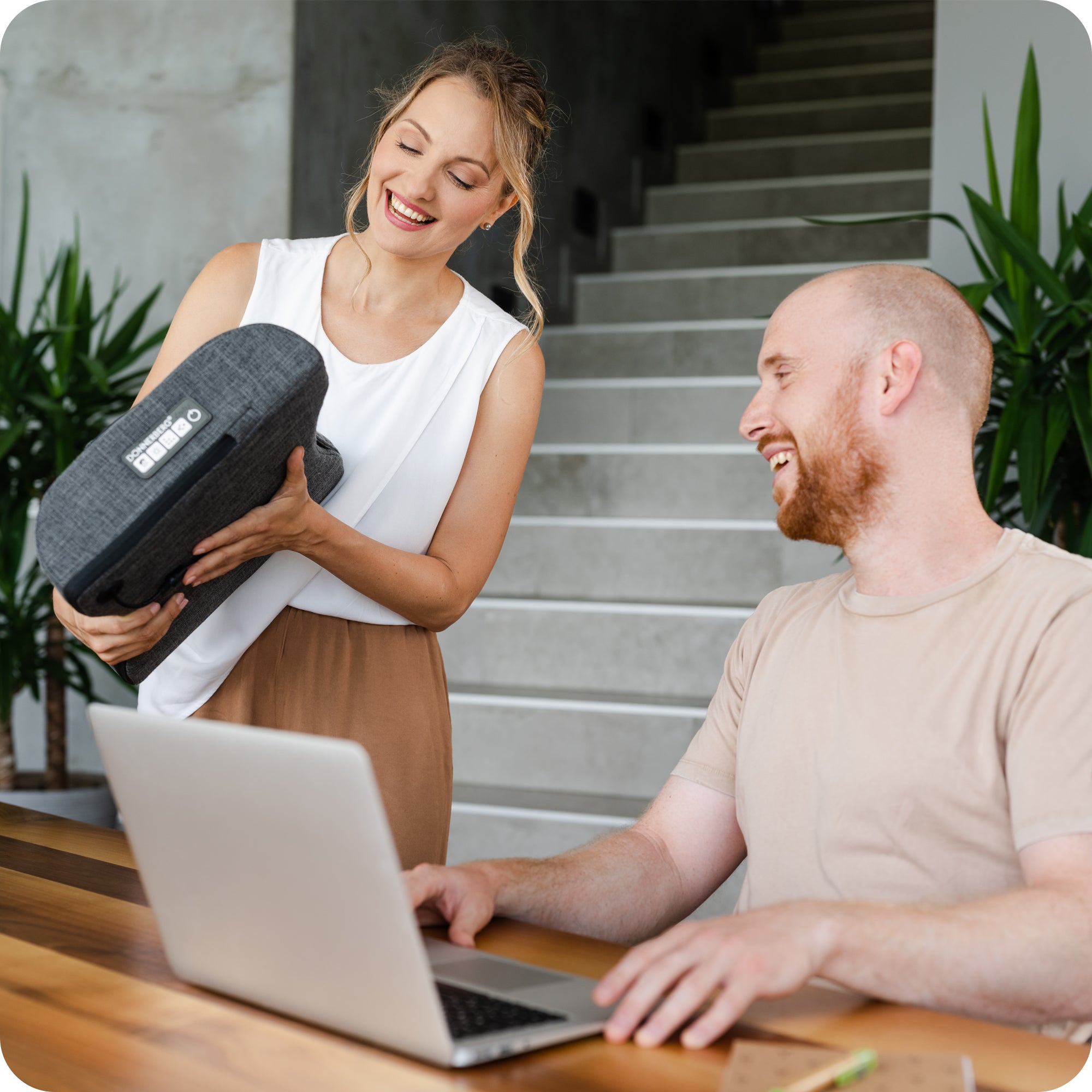 wife pleasantly surprising husband with shiatsu back massage pillow