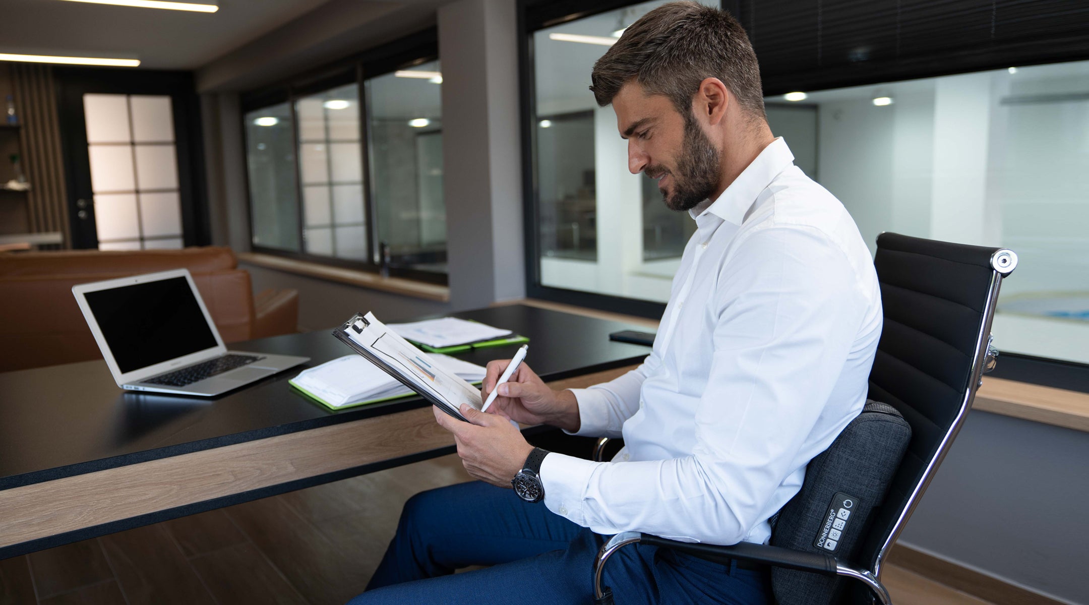 man seated at his office desk using Donnerberg portable back massager