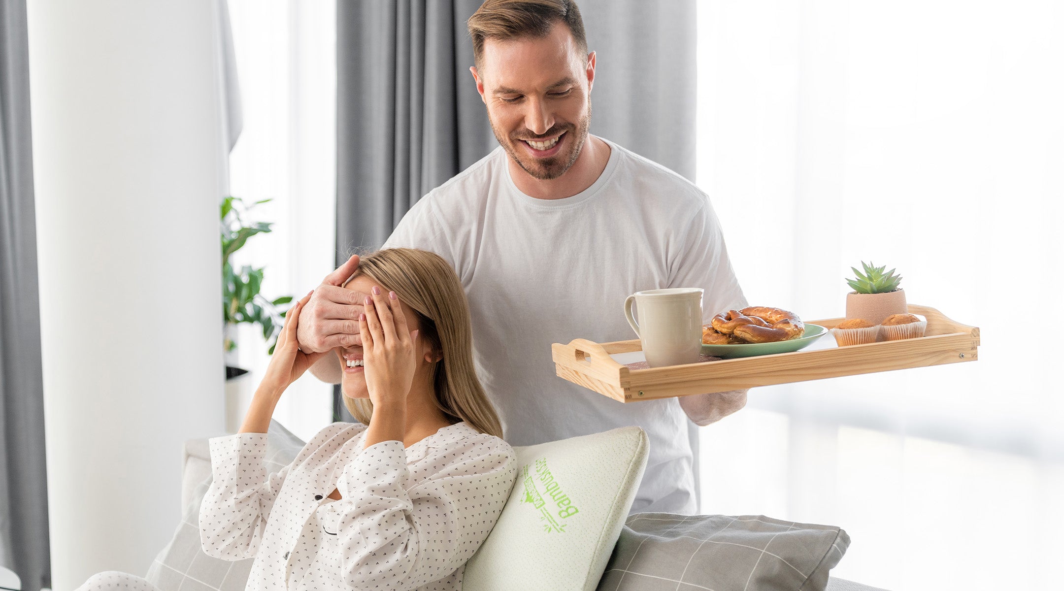 husband serving breakfast to wife resting on Donnerberg neck pillow