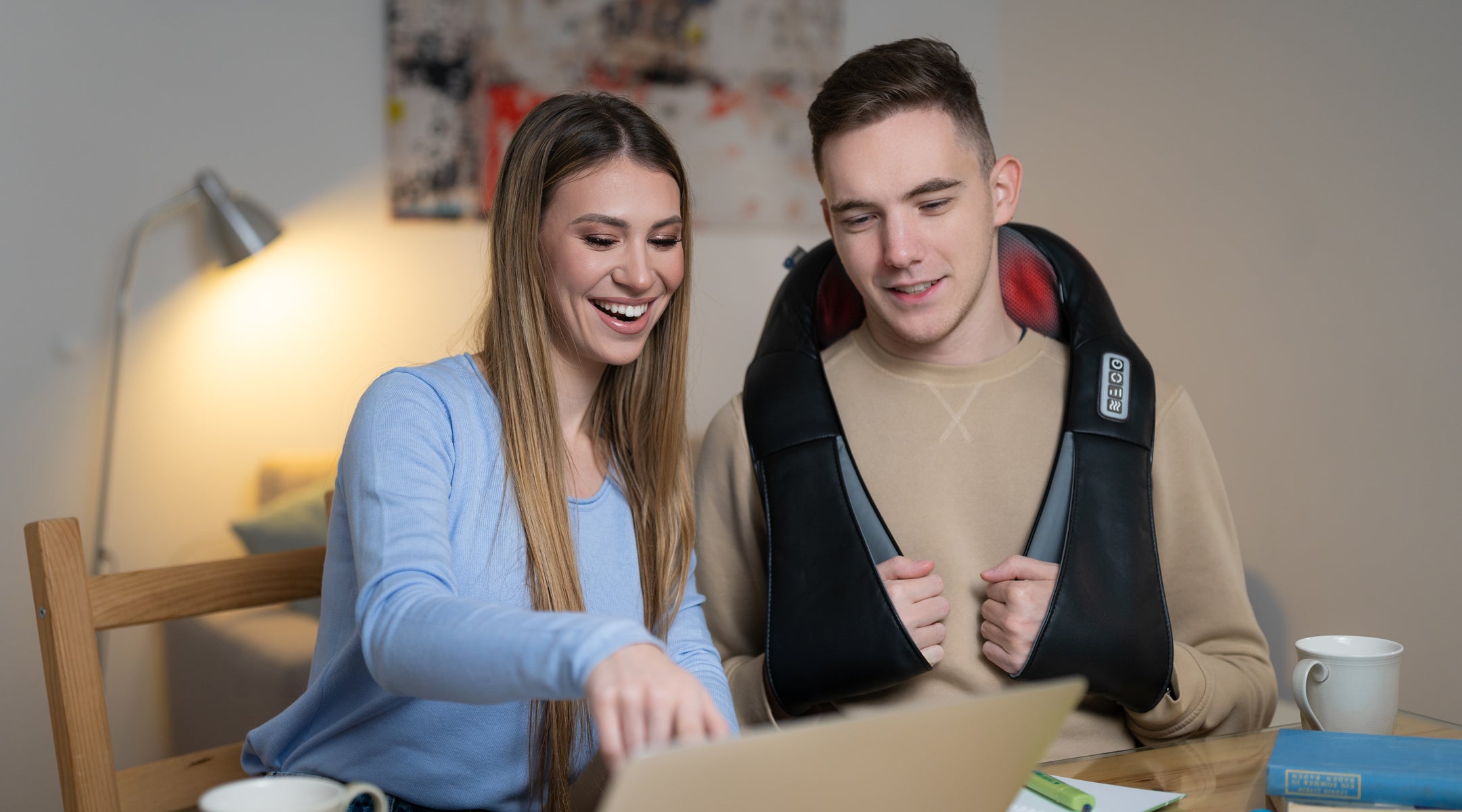 couple using black electric massager on neck and shoulders while sitting at laptop