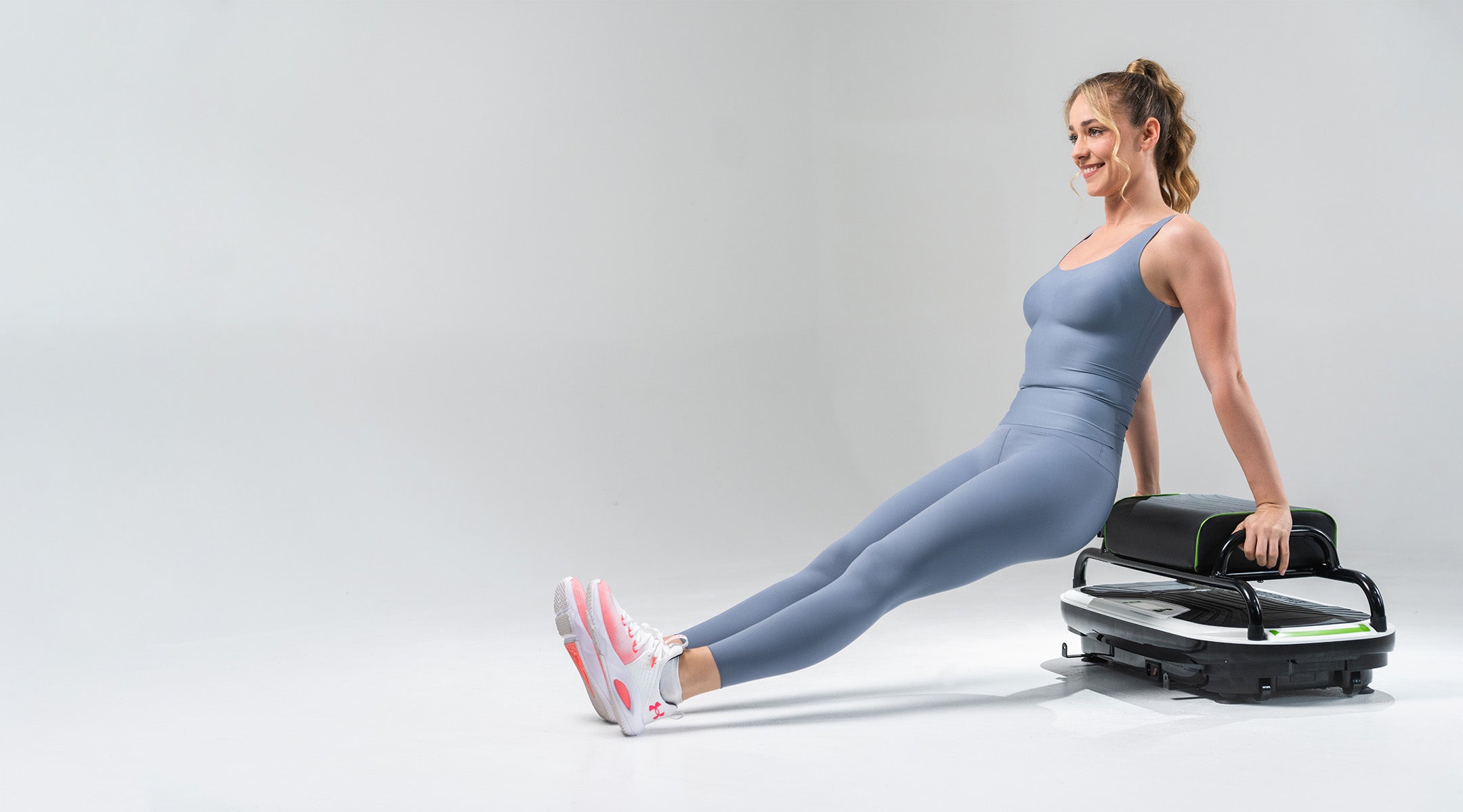 active young woman exercising on vibration machine seat