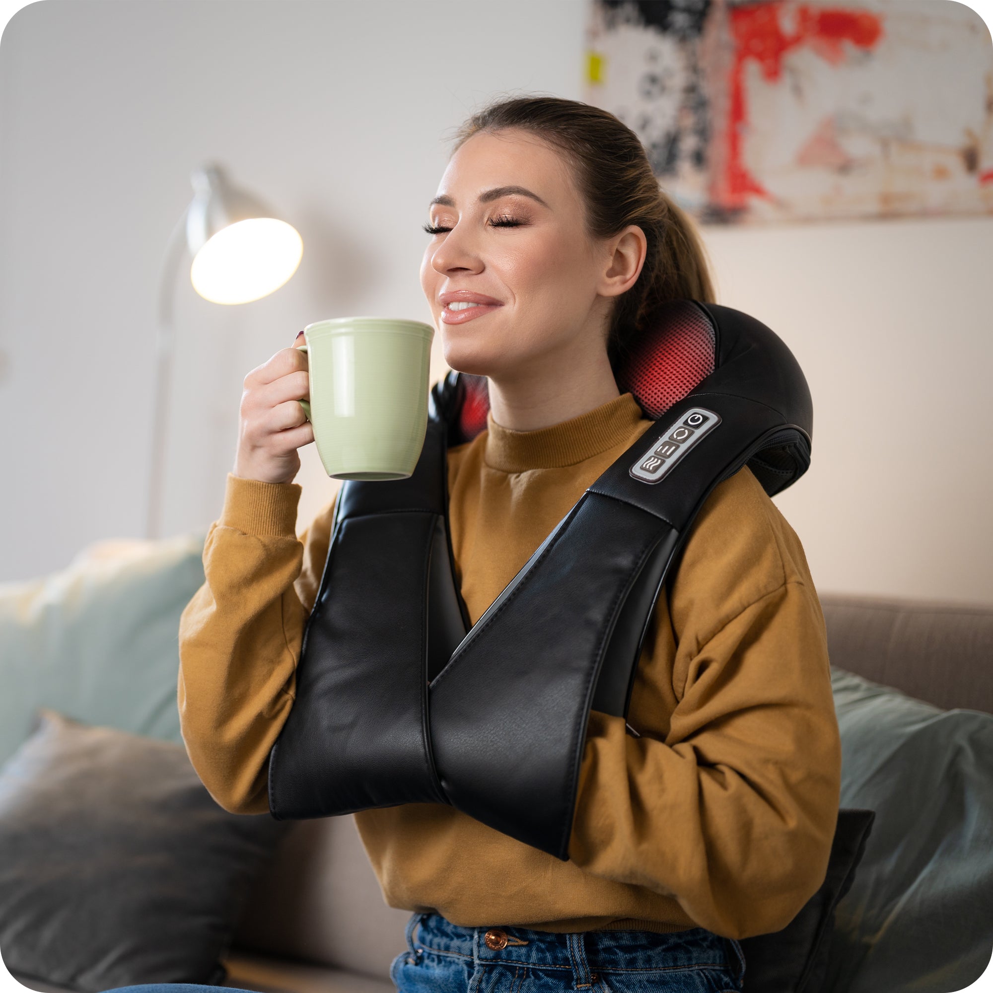 woman enjoying tea time while using electric neck and shoulder massager 