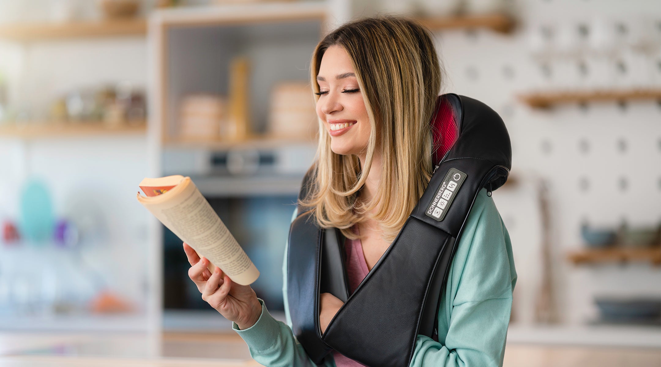 young woman reading a book while using massager for neck