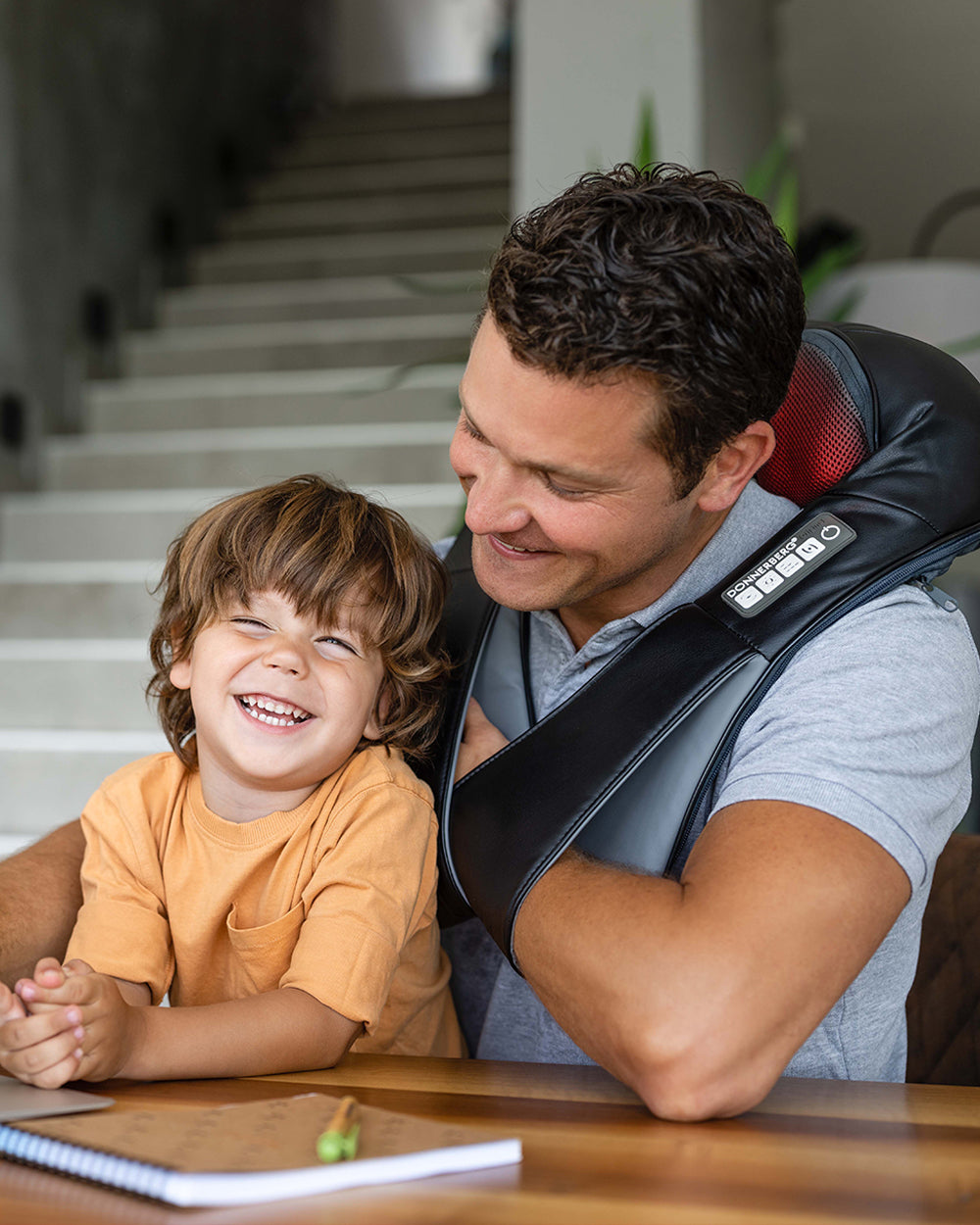 dad playing with son while using neck massager with heat