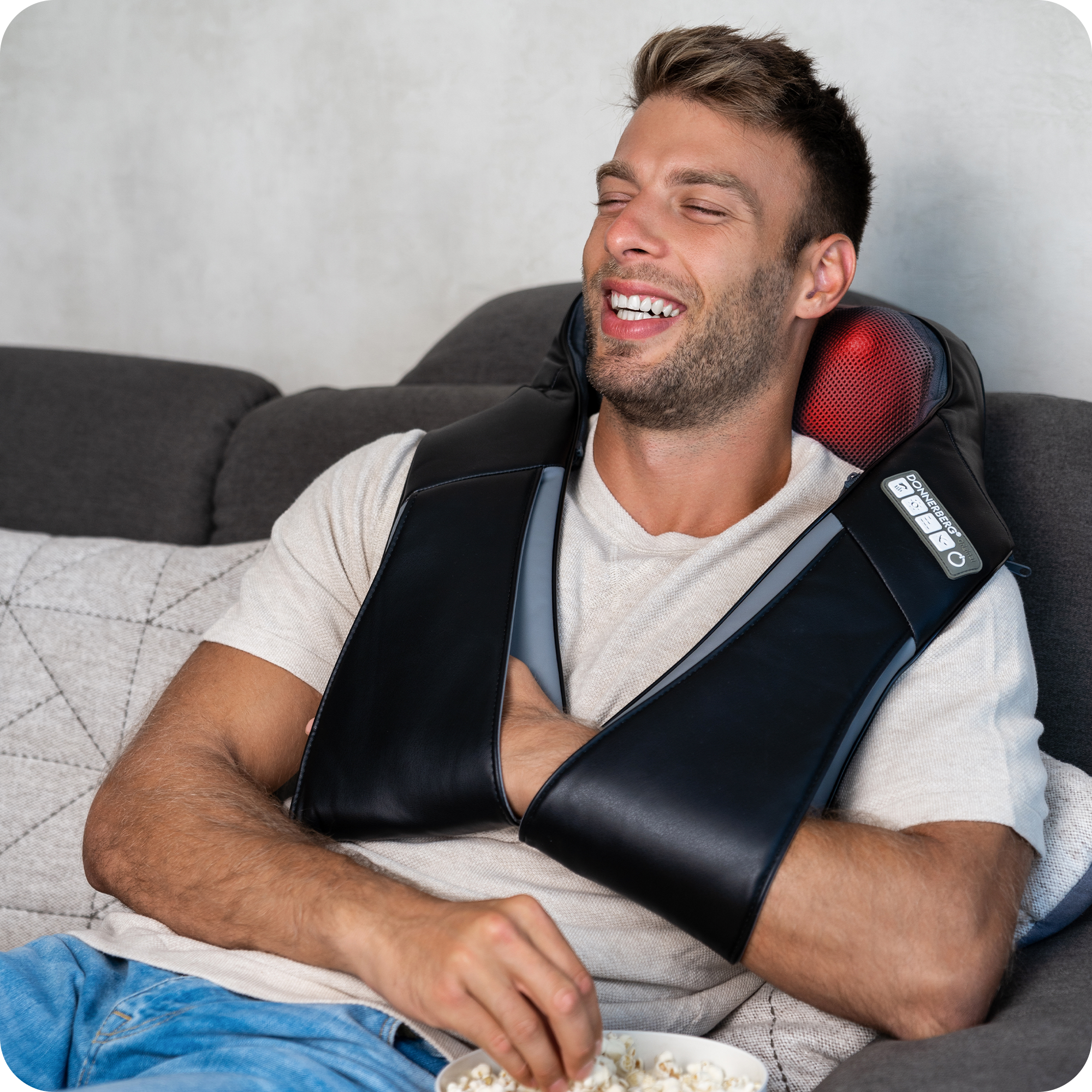 smiling young man eating popcorn and relaxing with donnerberg shiatsu neck and back massager