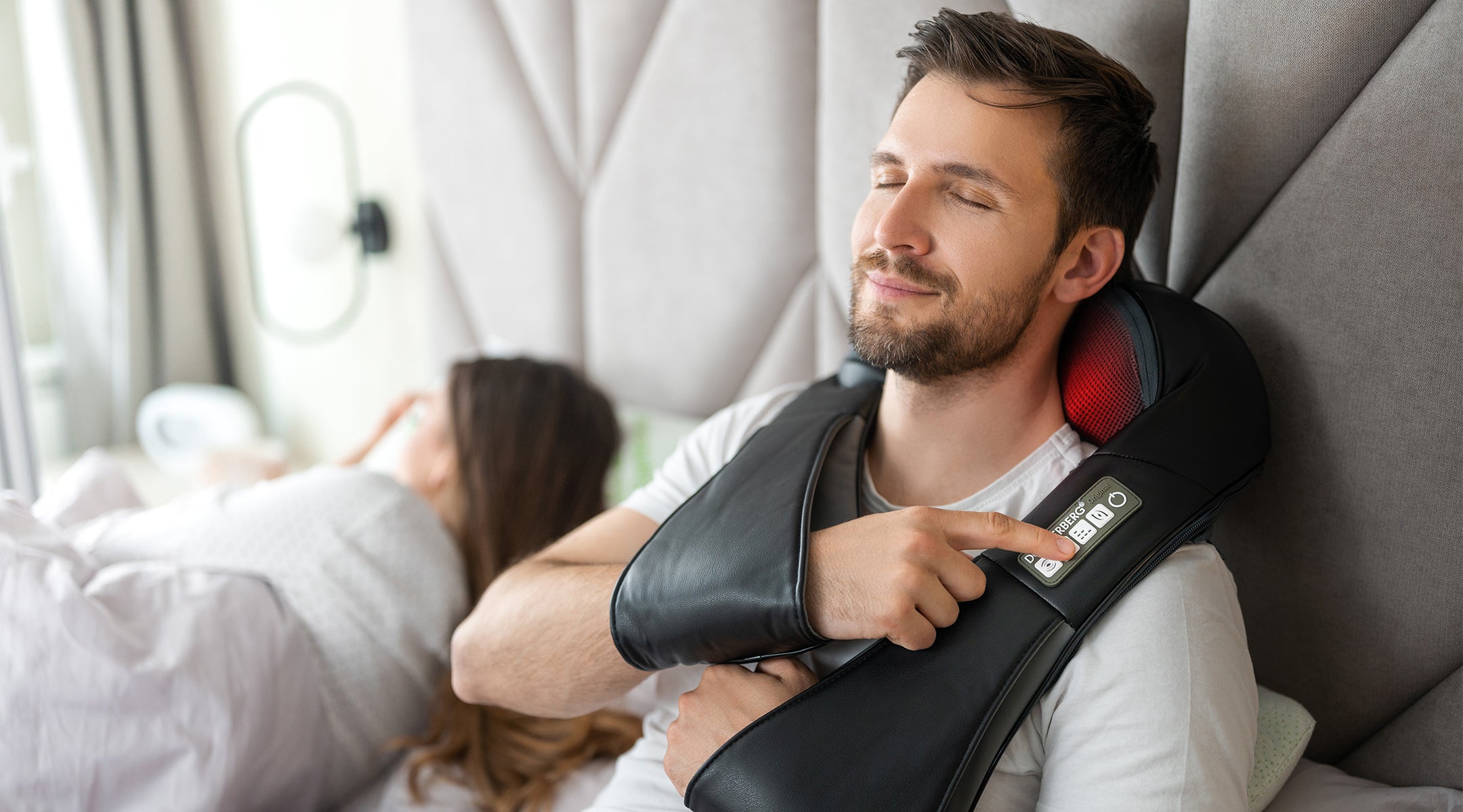 man using massager for soothing neck pain relief in bed